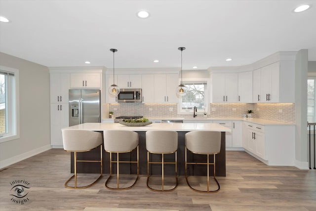 kitchen with hanging light fixtures, a kitchen island, appliances with stainless steel finishes, and light countertops