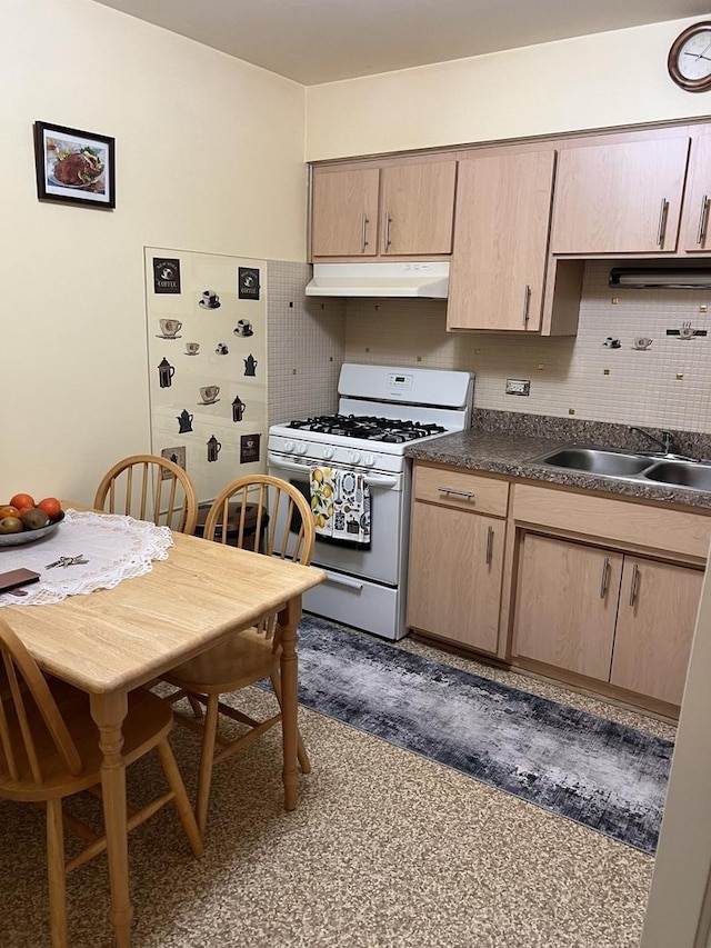 kitchen featuring dark countertops, white gas range, backsplash, and under cabinet range hood