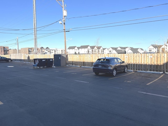 uncovered parking lot featuring fence and a residential view