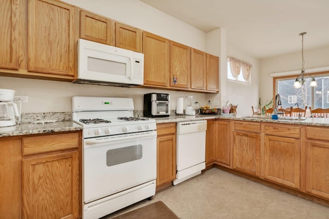 kitchen featuring white appliances, light stone countertops, a chandelier, pendant lighting, and a sink