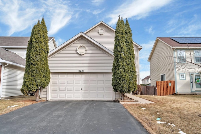 view of front of property featuring aphalt driveway, an attached garage, and fence