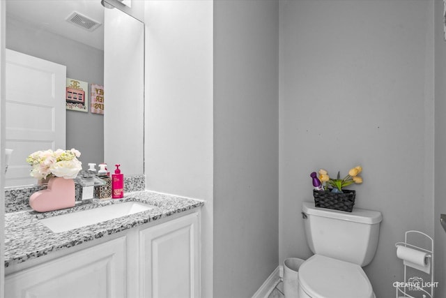 half bathroom featuring toilet, baseboards, visible vents, and vanity