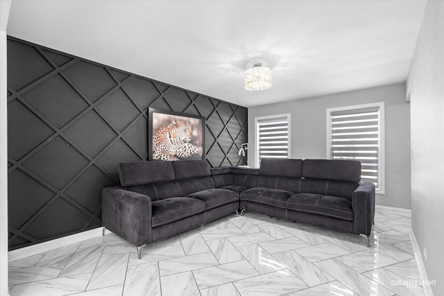 living area with marble finish floor, an accent wall, and baseboards