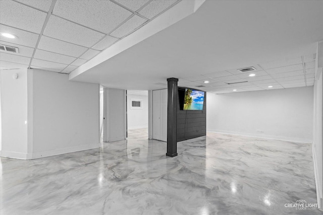 finished basement with a paneled ceiling, visible vents, and baseboards