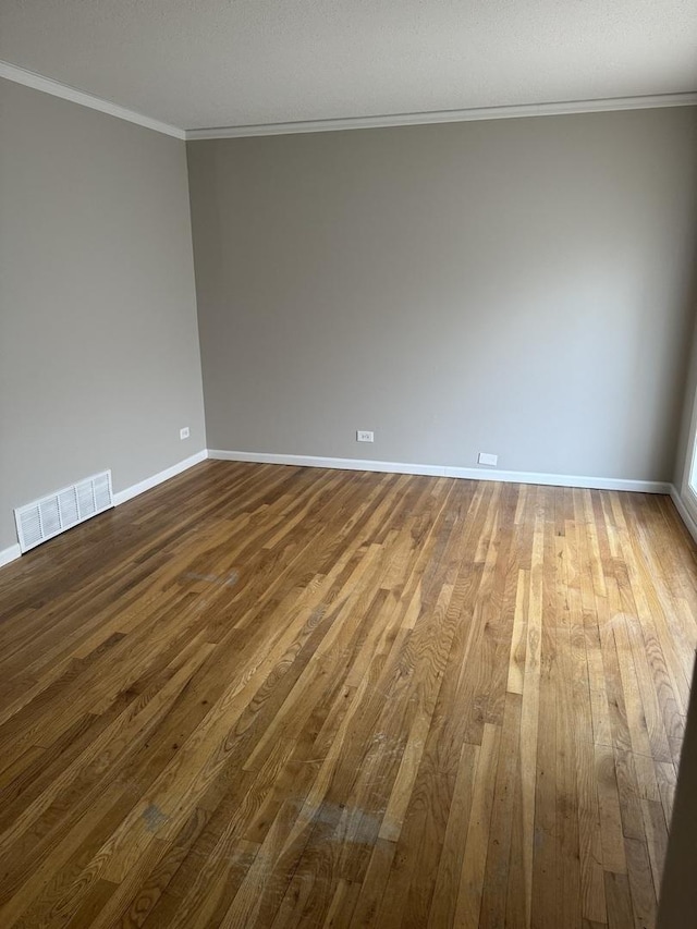 unfurnished room featuring baseboards, visible vents, hardwood / wood-style floors, and ornamental molding