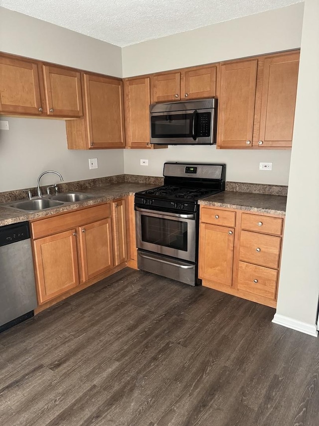 kitchen featuring stainless steel appliances, dark countertops, brown cabinets, and a sink