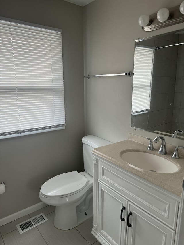 bathroom with tile patterned flooring, toilet, vanity, visible vents, and baseboards