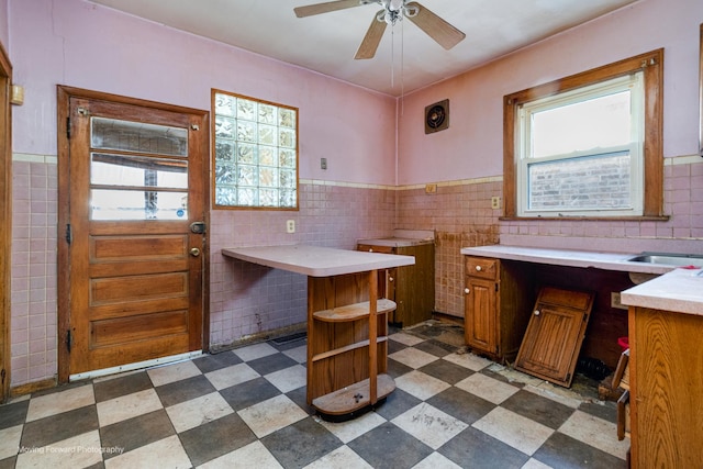 interior space featuring dark floors, wainscoting, ceiling fan, and tile walls