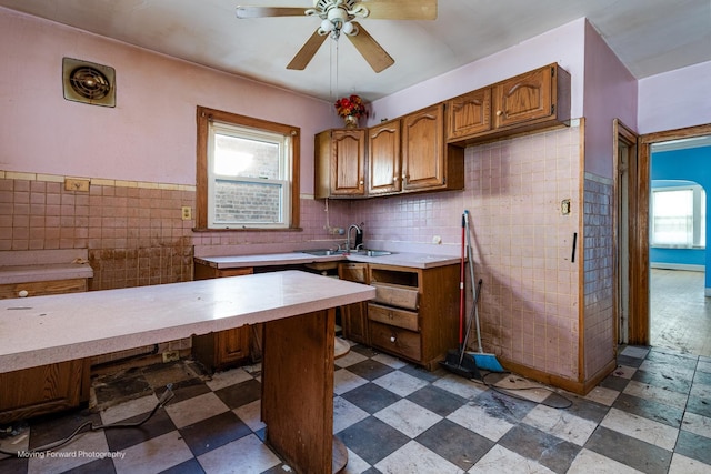 kitchen featuring brown cabinets, dark floors, light countertops, and tile walls