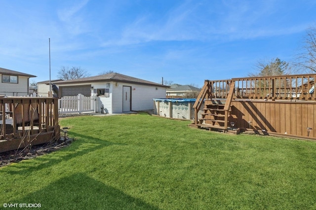 view of yard featuring a covered pool, a wooden deck, an outdoor structure, and fence