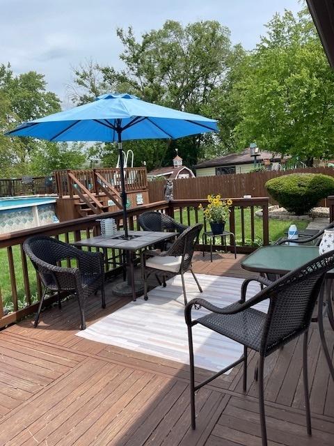 deck featuring a fenced in pool, outdoor dining area, and fence