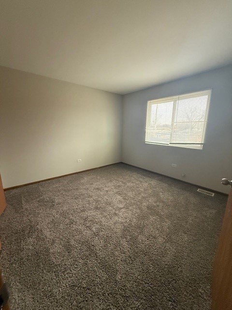 spare room with dark colored carpet and visible vents