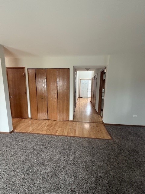 unfurnished bedroom featuring light wood-type flooring, light carpet, and baseboards