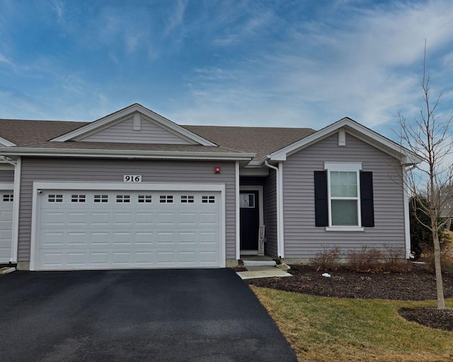 ranch-style home featuring a garage, driveway, and roof with shingles