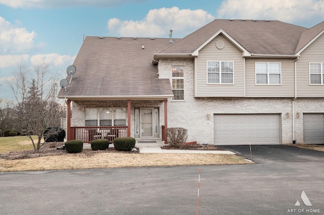 view of front facade featuring a garage, covered porch, brick siding, and driveway