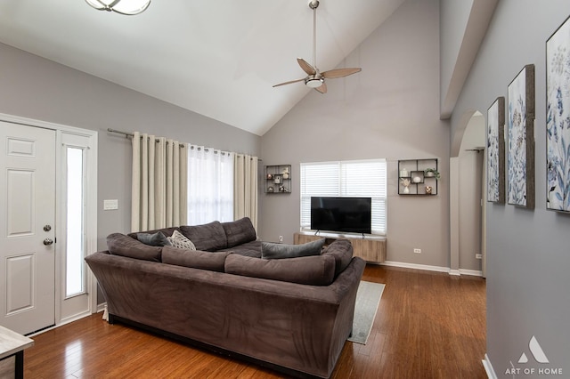 living room with arched walkways, dark wood-style flooring, a ceiling fan, high vaulted ceiling, and baseboards