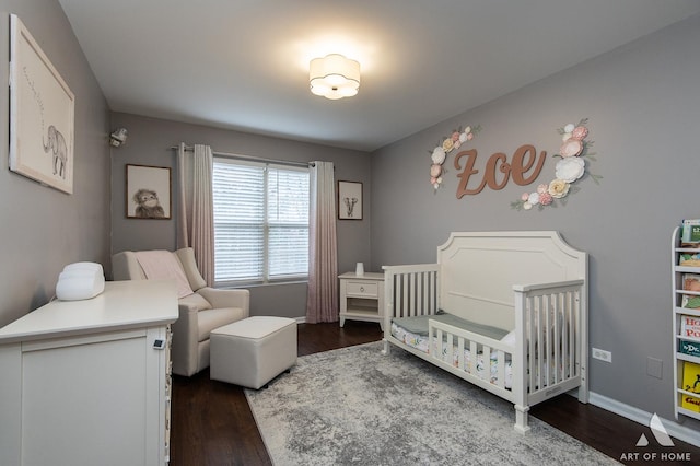 bedroom featuring a nursery area, dark wood-type flooring, and baseboards