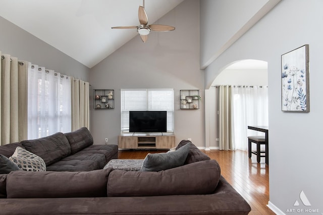 living room with a ceiling fan, light wood-style flooring, arched walkways, and a wealth of natural light