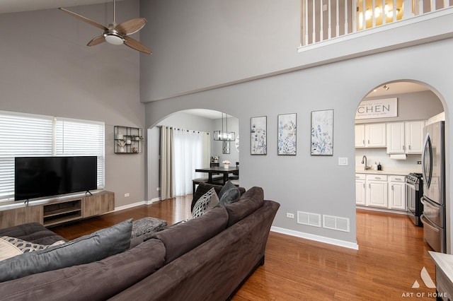 living area with arched walkways, light wood-style flooring, and baseboards