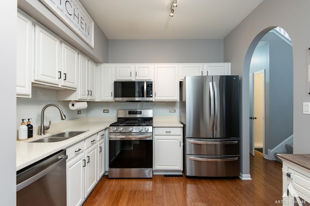 kitchen with a sink, white cabinets, light countertops, appliances with stainless steel finishes, and dark wood-style floors