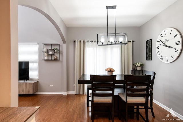 dining room featuring a notable chandelier, dark wood-style flooring, arched walkways, and baseboards