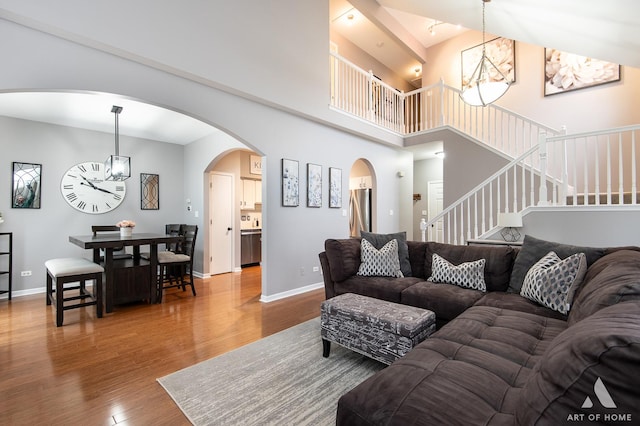 living area featuring baseboards, stairway, wood finished floors, and a notable chandelier