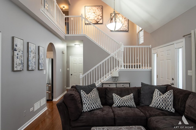 living room with stairs, wood finished floors, a towering ceiling, and baseboards