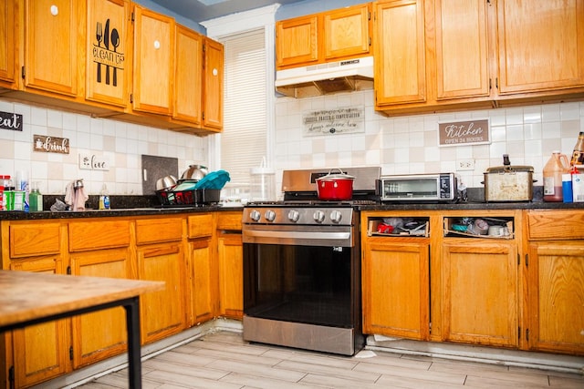 kitchen with a toaster, tasteful backsplash, stainless steel range with gas stovetop, and under cabinet range hood