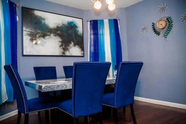 dining room featuring a chandelier, baseboards, and wood finished floors