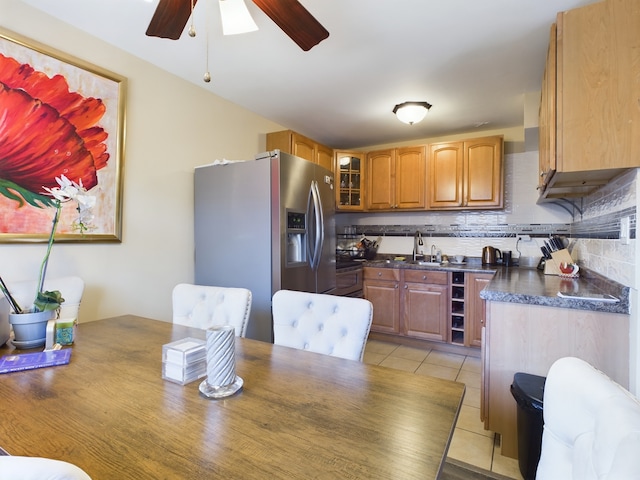 kitchen with light tile patterned flooring, stainless steel appliances, tasteful backsplash, dark countertops, and glass insert cabinets