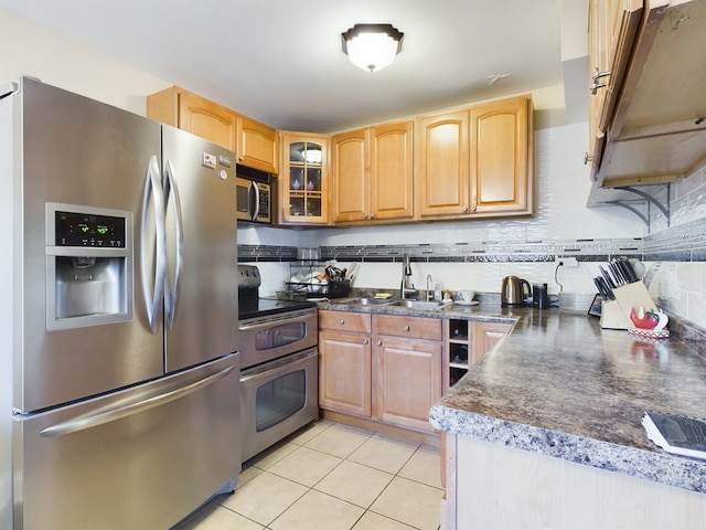 kitchen featuring dark countertops, backsplash, appliances with stainless steel finishes, light tile patterned flooring, and a sink