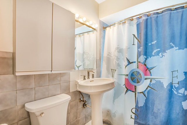 bathroom with toilet, curtained shower, a sink, and tile walls