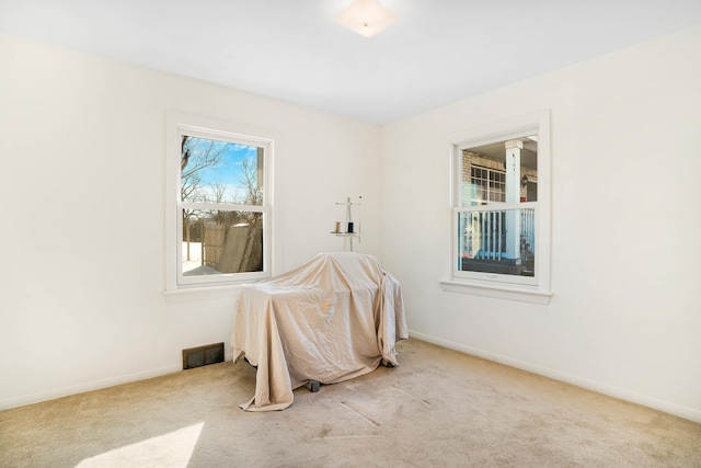 spare room featuring light colored carpet, visible vents, and baseboards