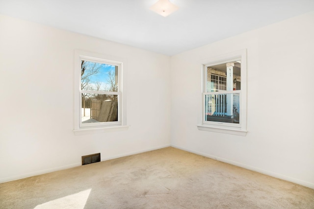 empty room featuring light carpet, visible vents, and baseboards