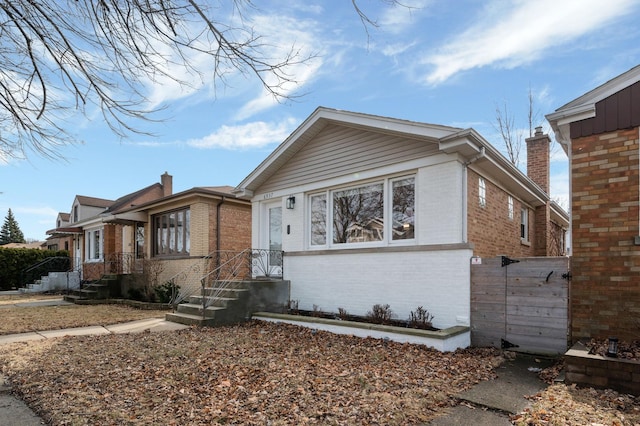 bungalow featuring a chimney and brick siding