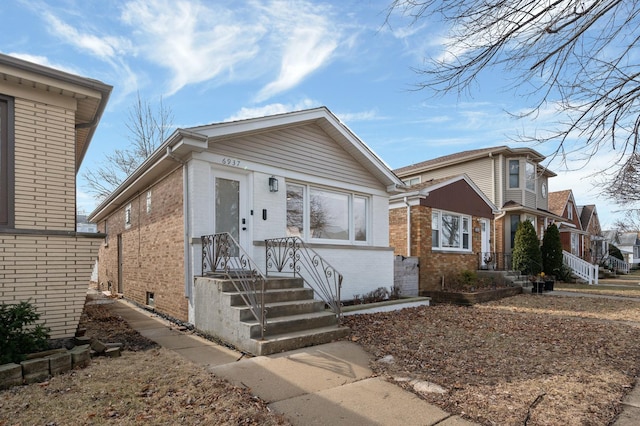 bungalow featuring brick siding