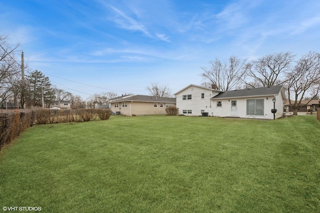 rear view of property featuring a yard, a chimney, and fence