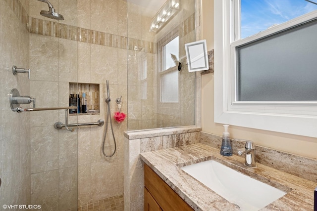 bathroom with tiled shower and vanity