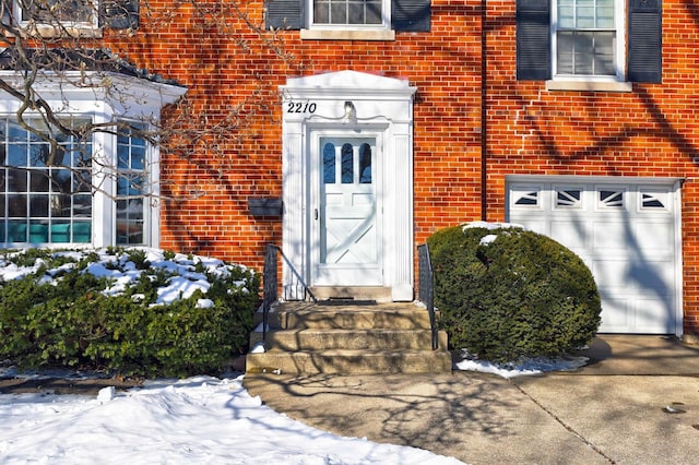 entrance to property with a garage and brick siding