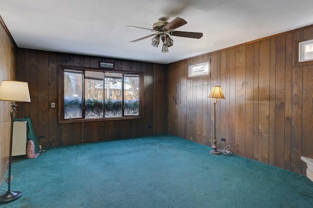 spare room with carpet flooring, ceiling fan, and wood walls