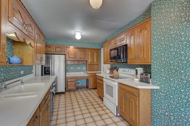 kitchen featuring wallpapered walls, white electric stove, black microwave, and a sink