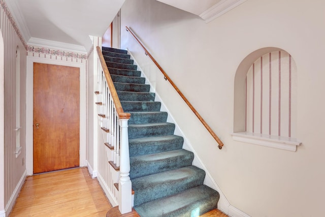 staircase with crown molding, baseboards, and wood finished floors