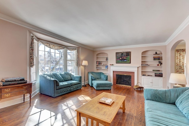 living room with baseboards, wood finished floors, crown molding, built in shelves, and a fireplace