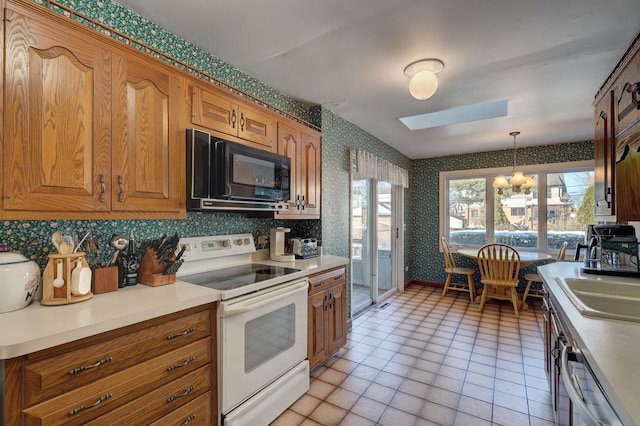 kitchen featuring white electric range, brown cabinetry, a sink, black microwave, and wallpapered walls