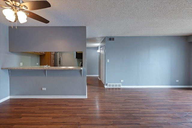 kitchen featuring a peninsula, dark wood-style flooring, visible vents, light countertops, and appliances with stainless steel finishes