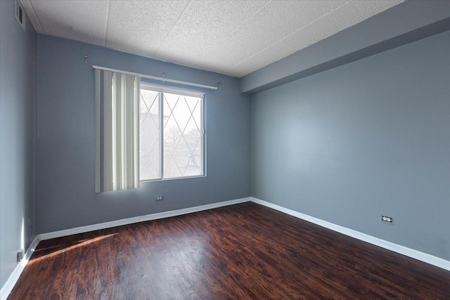 spare room with visible vents, baseboards, and dark wood finished floors