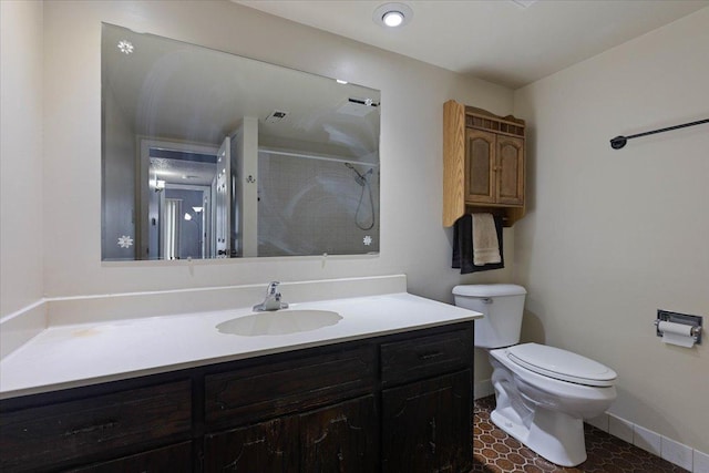 bathroom with vanity, walk in shower, toilet, and baseboards