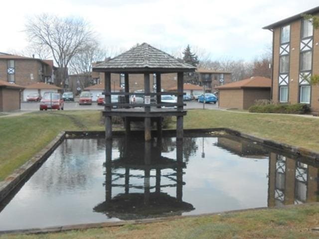 view of dock with a water view, a yard, and a gazebo