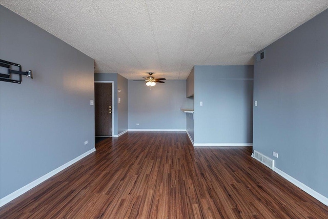 spare room with ceiling fan, visible vents, dark wood finished floors, and baseboards