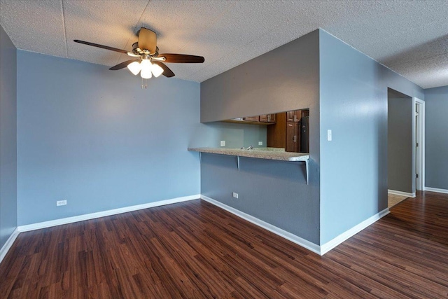 kitchen with dark wood-style flooring, light countertops, a ceiling fan, a peninsula, and baseboards